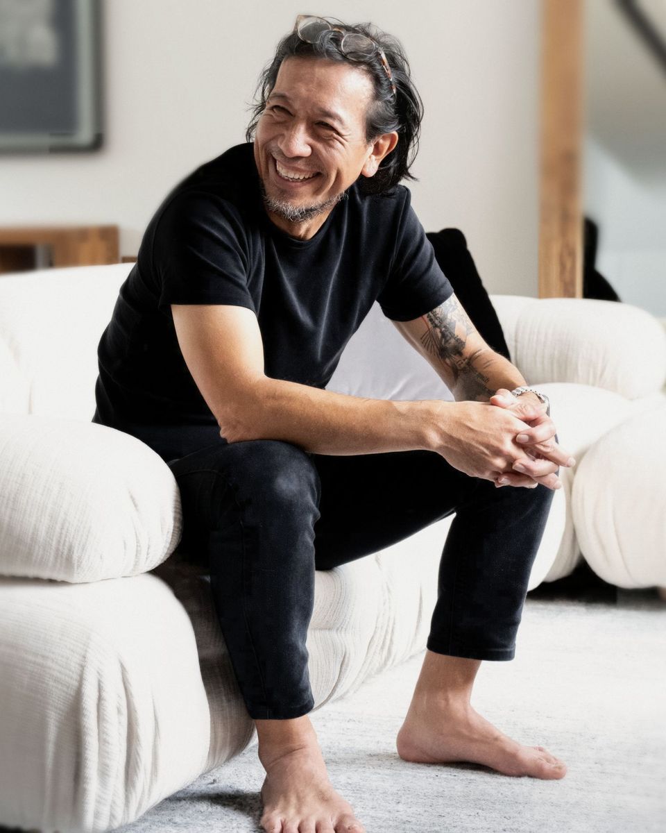 Georges Hung, seated on a white sofa, smiling