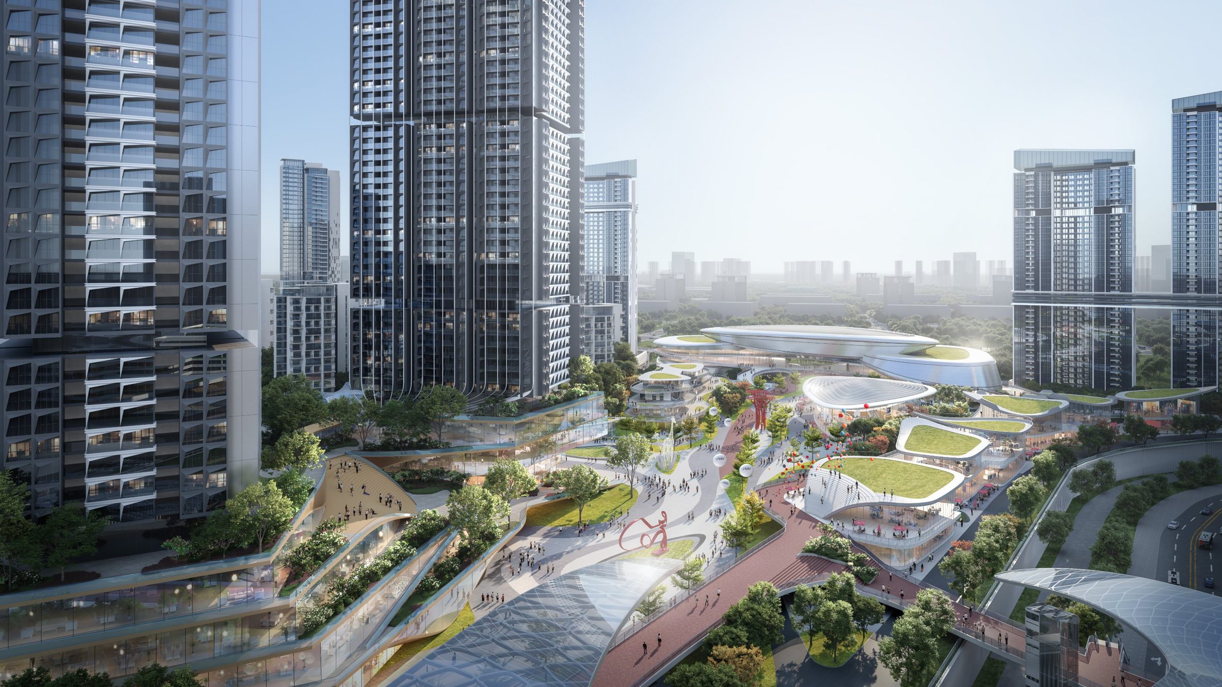 Aerial view: residential towers frame the retail centre, a winding park and pavilions with green roofs, and the red running track crossing the site
