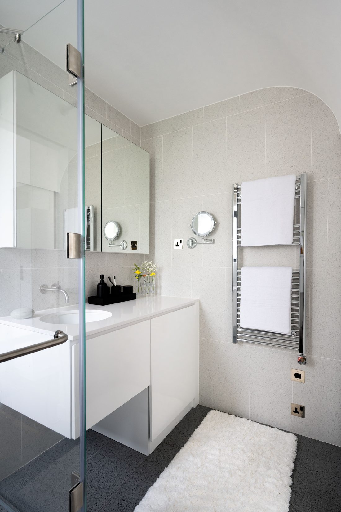 The bathroom: a glass shower screen, white vanity and heated towel rail