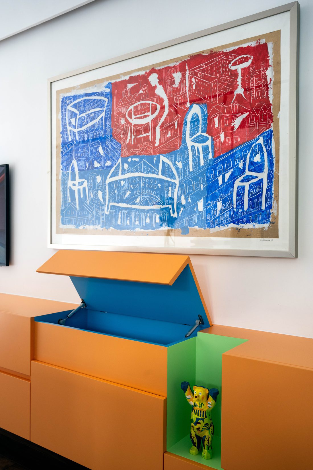 A cupboard in the apricot cabinet opened to show blue and green linings beneath a painting
