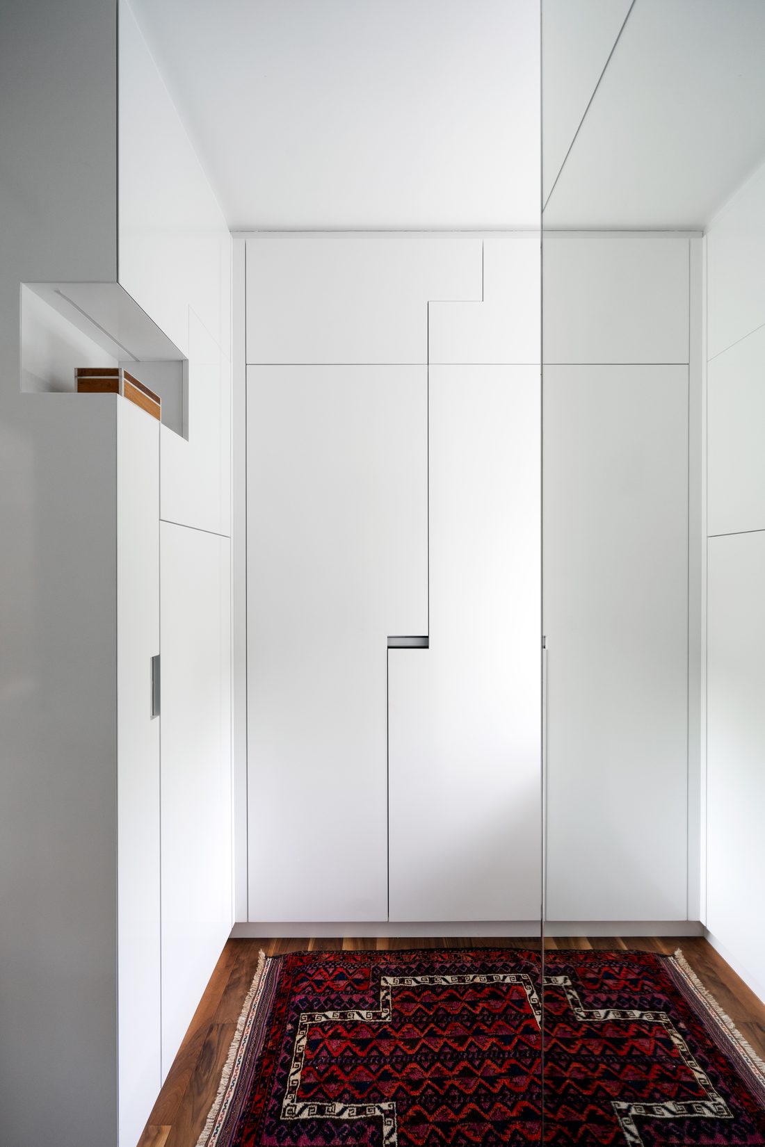 White flush wardrobe doors with slim handles above a red rug