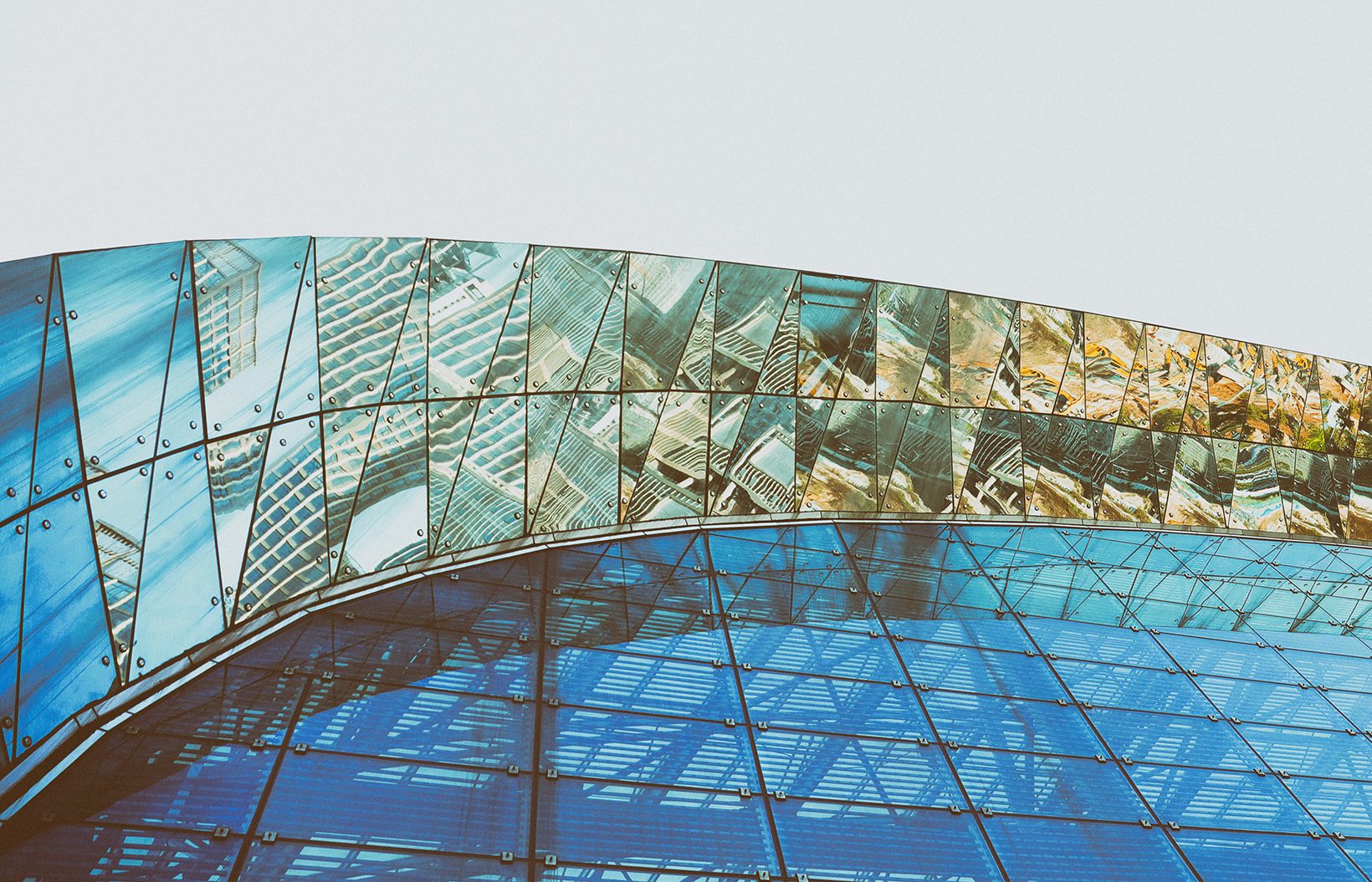 The entry arch: a curved band of glass reflecting the plaza above blue glazing