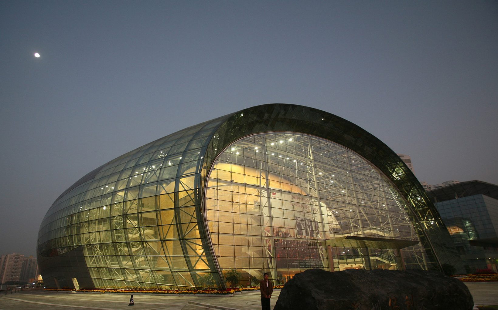 The theatre at dusk, its glass shell lit from within