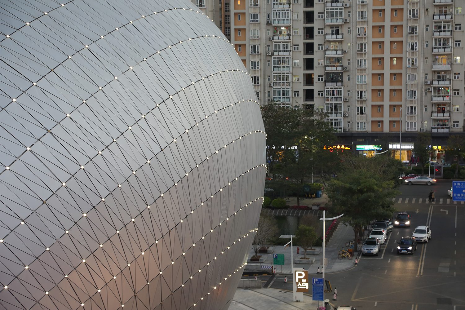 The theatre’s metal skin curving above the street, apartment towers behind