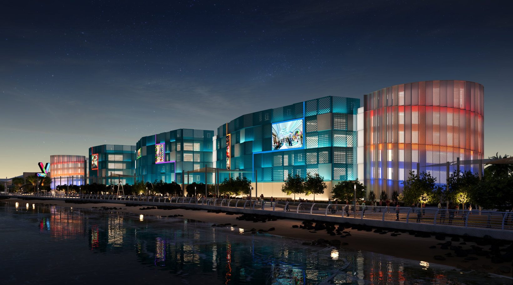 The same view at night: the perforated blue panels lit from within, reflected in the water along the promenade