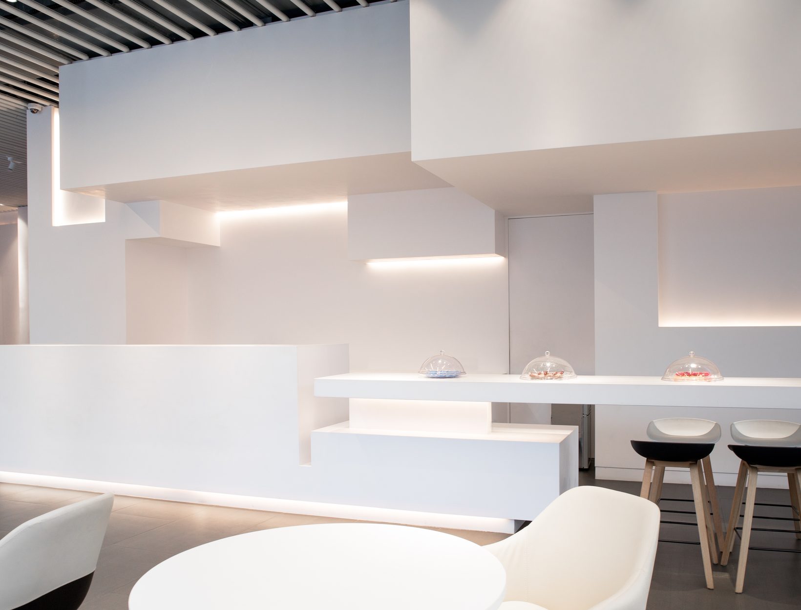 The bar counter stepping along the wall, with stools and soft light beneath