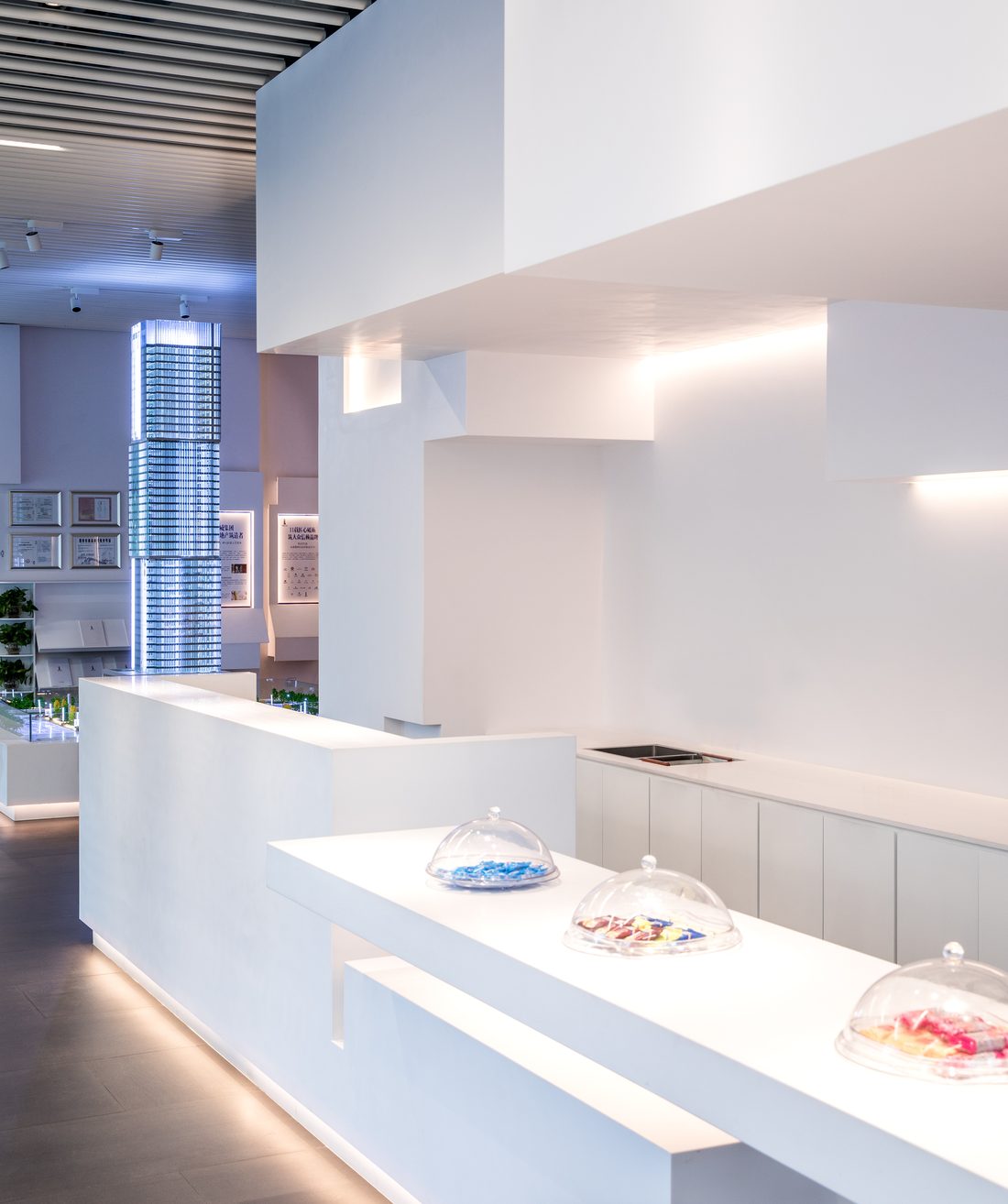 Close view of the white counter and wall volumes, glass domes on the counter