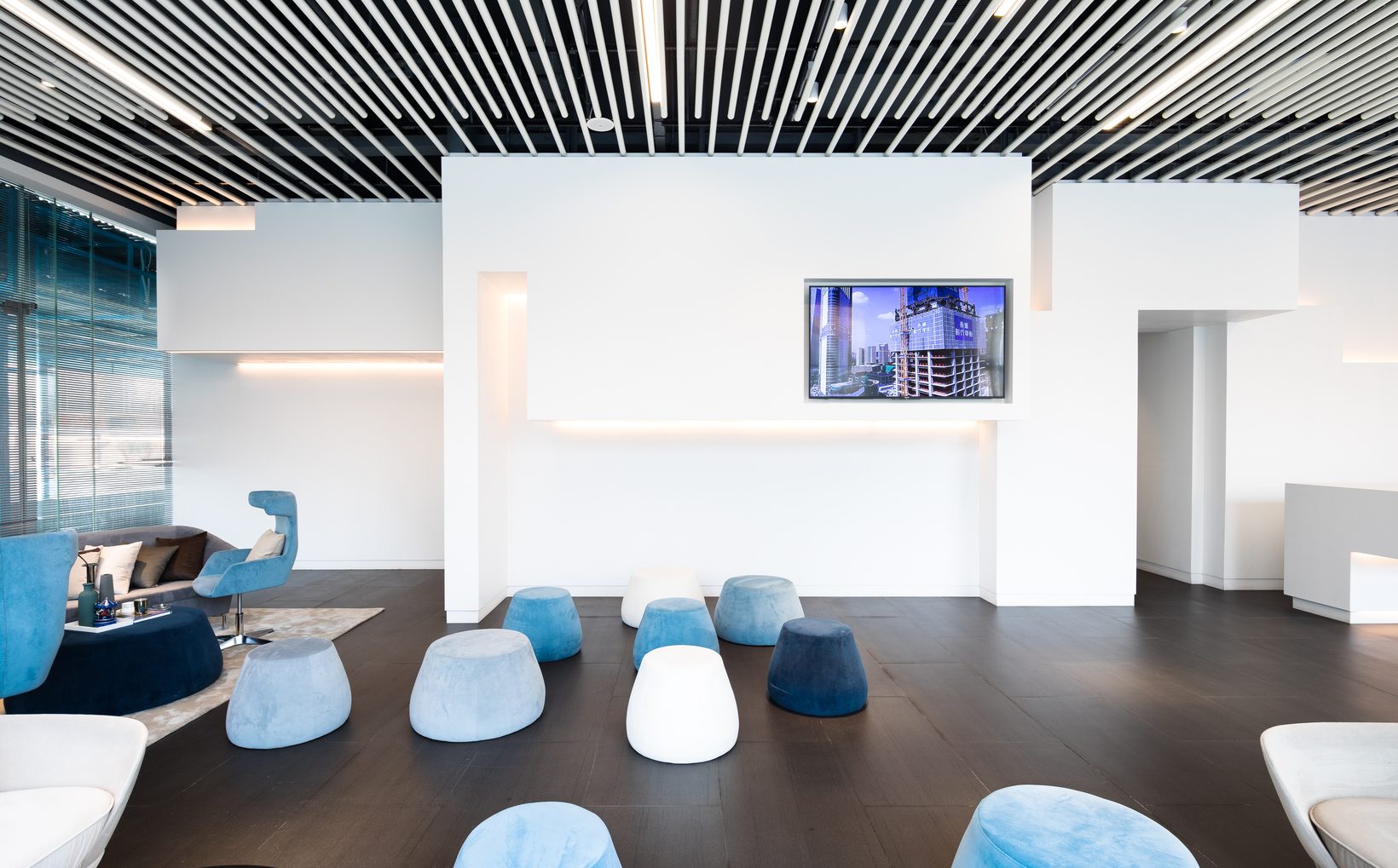 The lounge: blue and white poufs and armchairs on a timber floor before the white feature wall