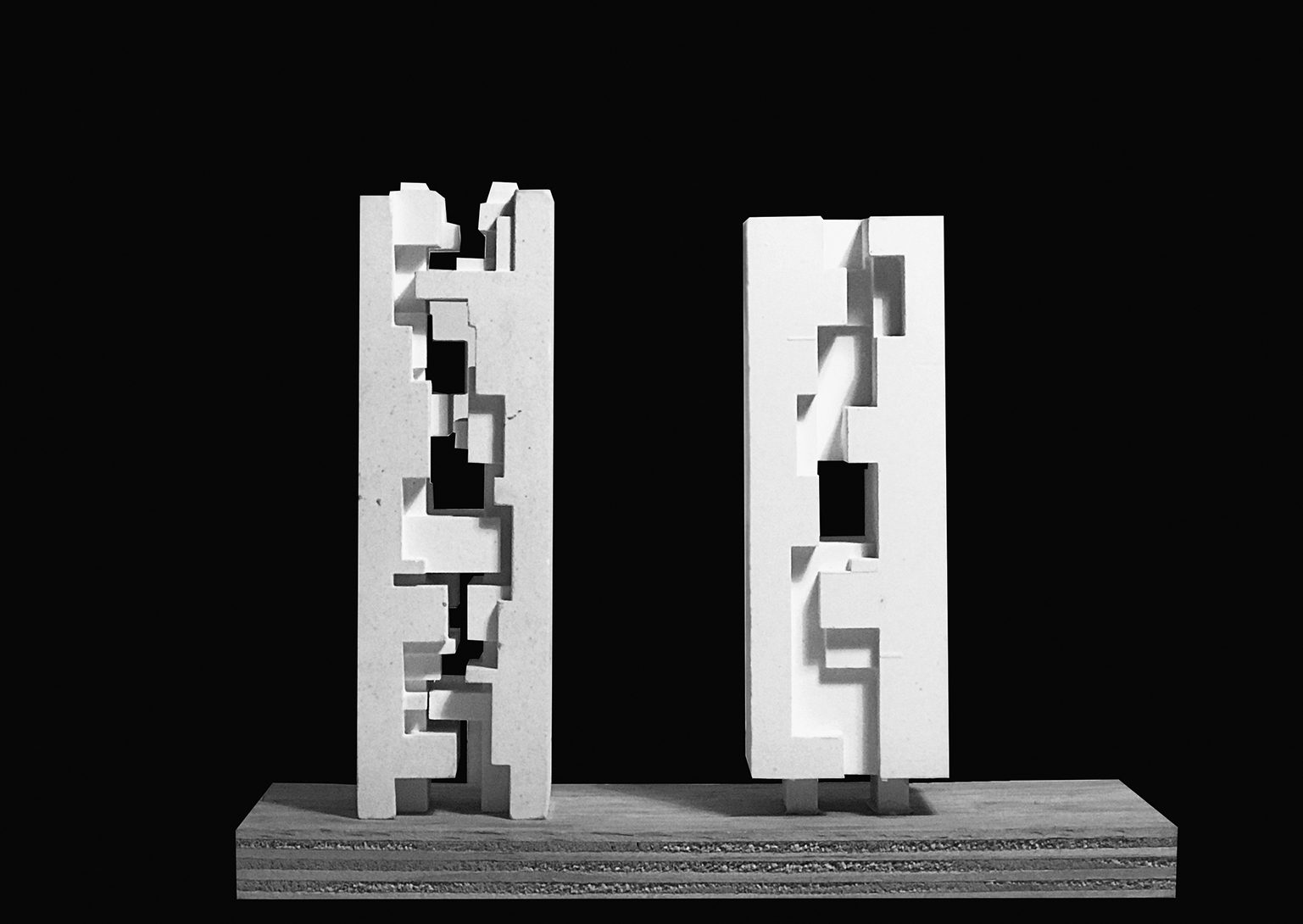 Physical model in white: two slender towers standing apart, their facing sides cut with interlocking voids