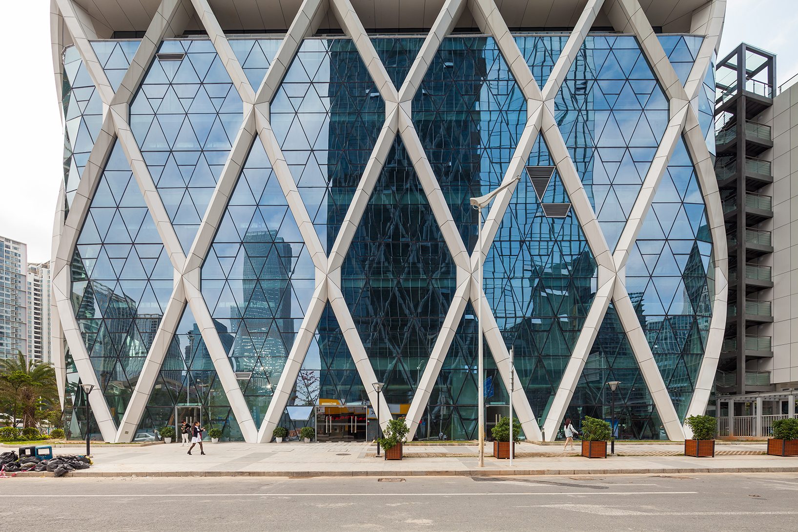 Street-level view of the base: wide diagonal columns framing the glass lobby