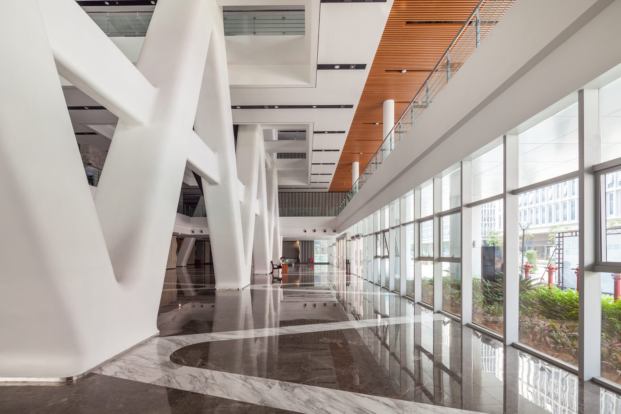 A long glazed gallery along the base, white diagonal columns on one side