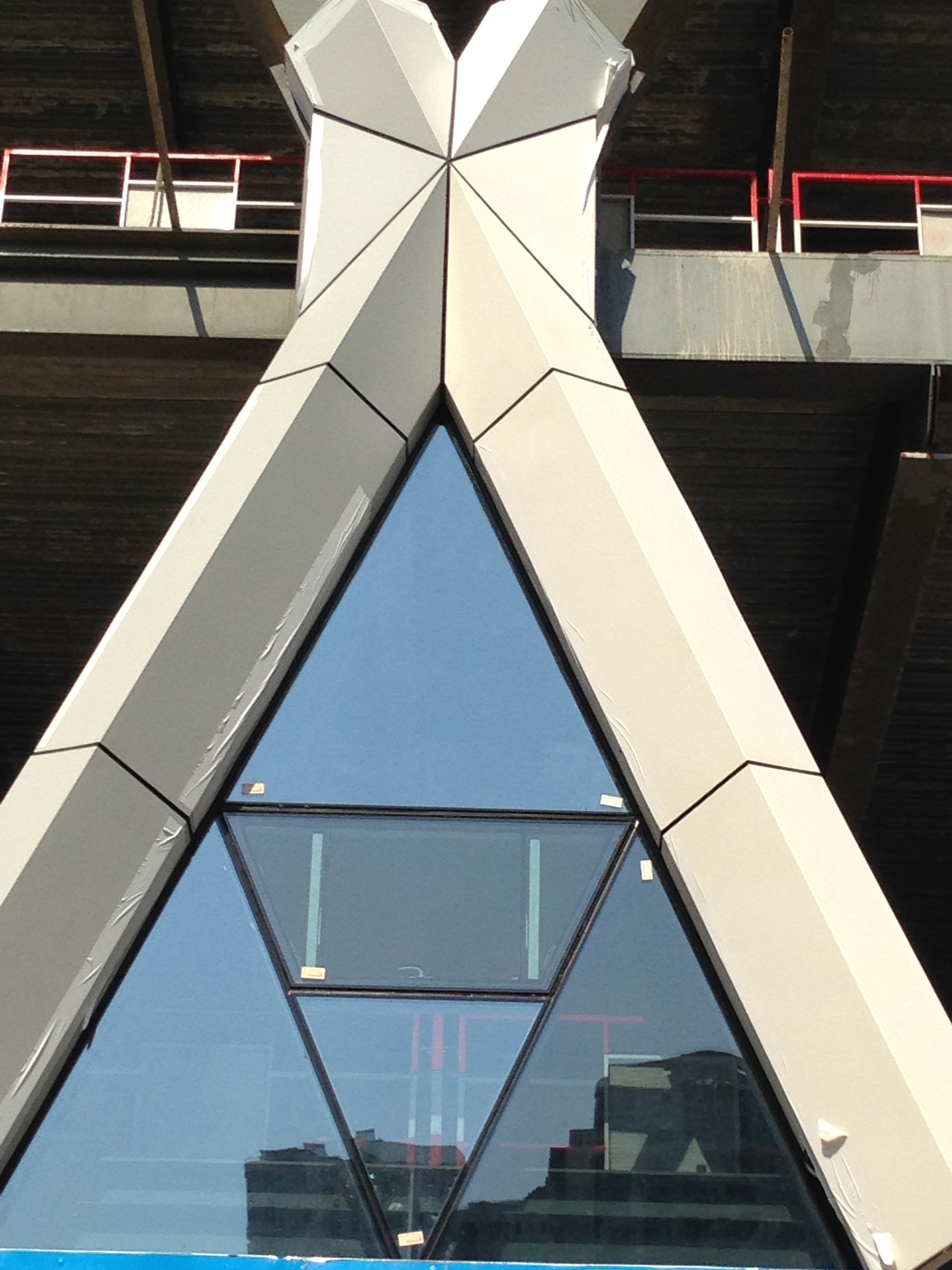 Close photograph of a diagrid node clad in white aluminium panels over glass